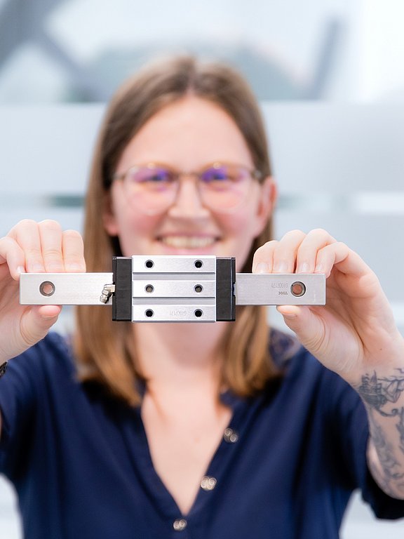 Laura Doblhofer, Produktmanagerin bei HENNLICH, hält eine Linearführung in beiden Händen.