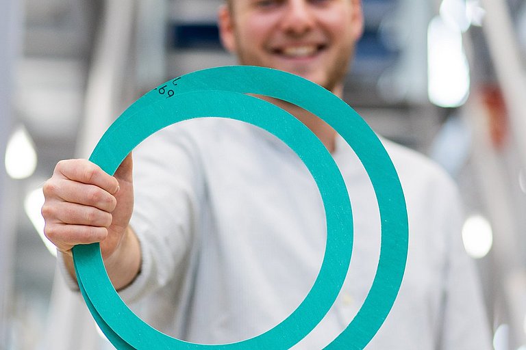 Flachdichtungen_NicoSmuda Nico Smuda, Techniker bei HENNLICH, hält zwei Flachdichtungen in einer Hand