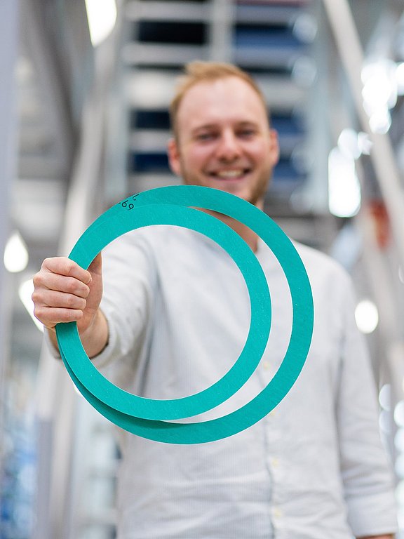 Flachdichtungen_NicoSmuda Nico Smuda, Techniker bei HENNLICH, hält zwei Flachdichtungen in einer Hand